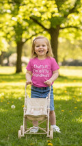 Child in a pink shirt with a stroller in a park